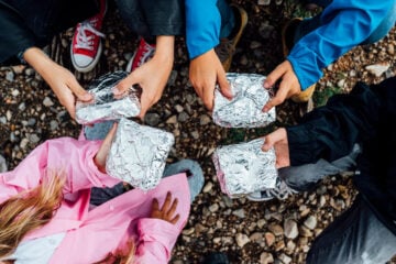 four people preparing to unwrap foil wrapped sandwiches