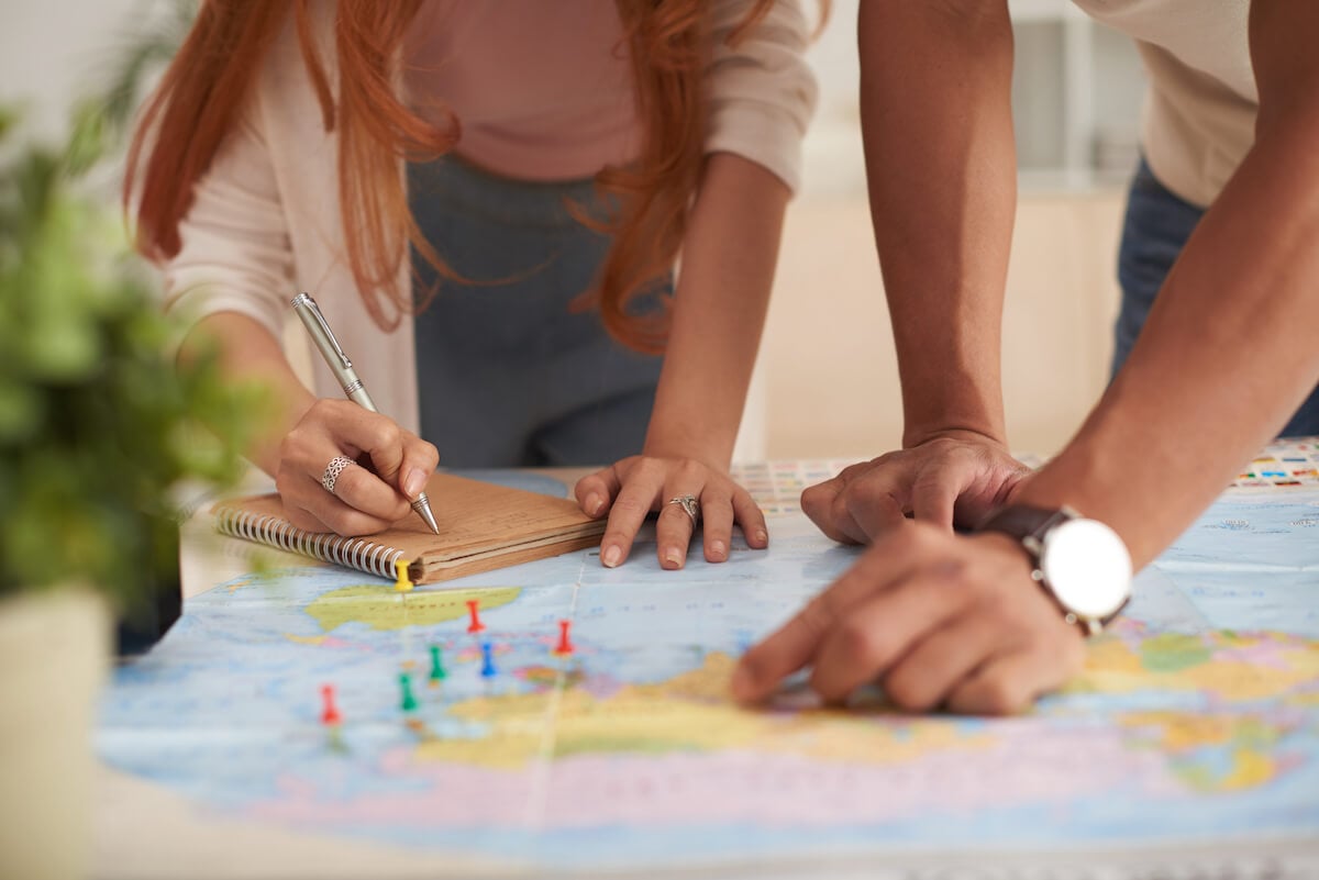 man and woman planning a travel route with a map using pins.