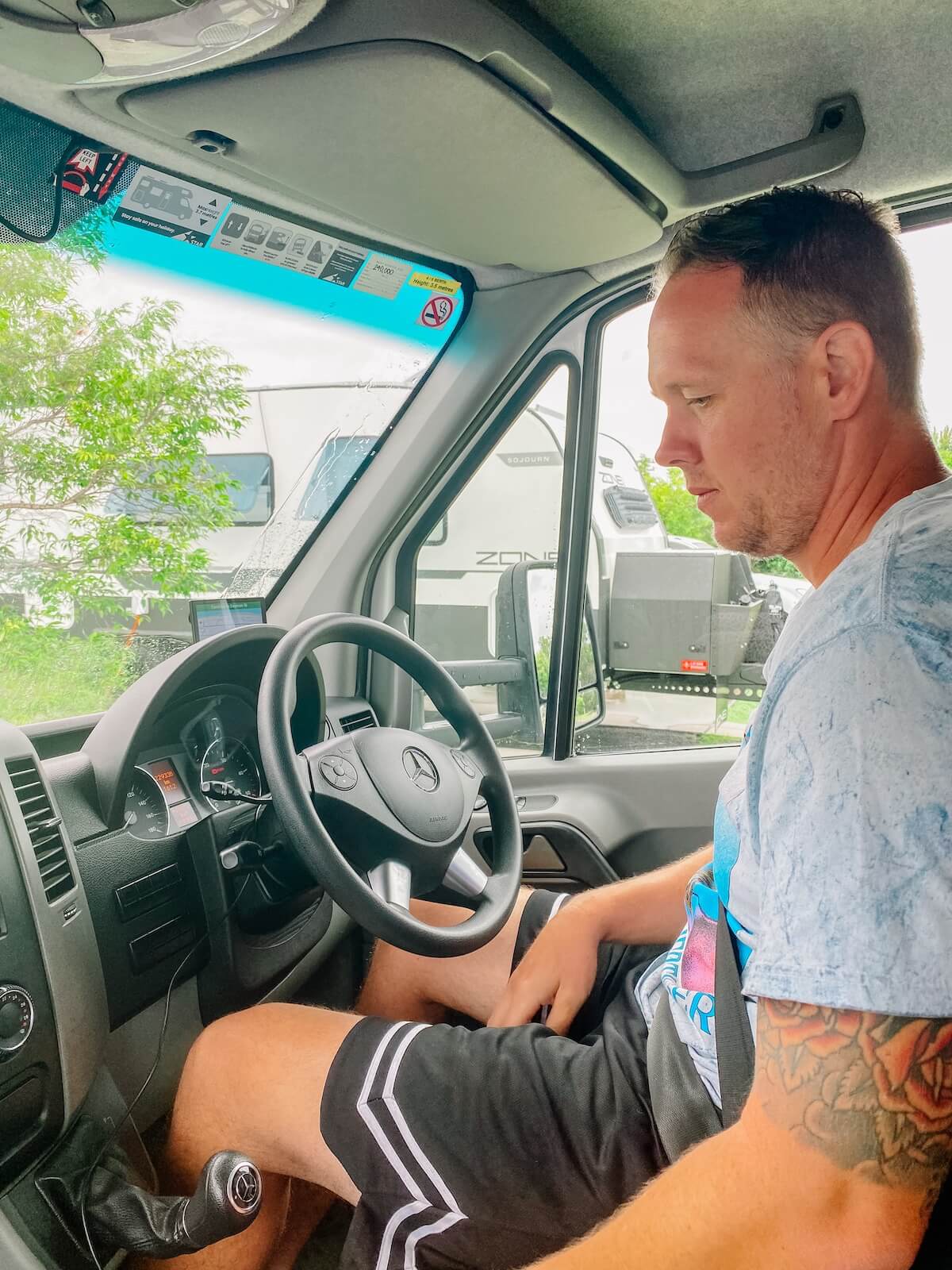 man sitting in drivers seat of motorhome.